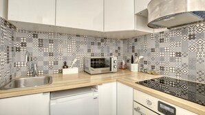 A kitchen with patterned backsplash, a toaster, a sink, and a dishwasher. - Lola Homes " Contemporary and warm apartment " (Puteaux)
