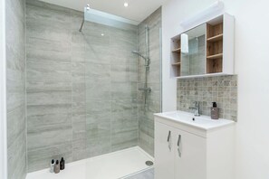 A modern bathroom with a glass-enclosed shower, a white sink, and a mirror above it.