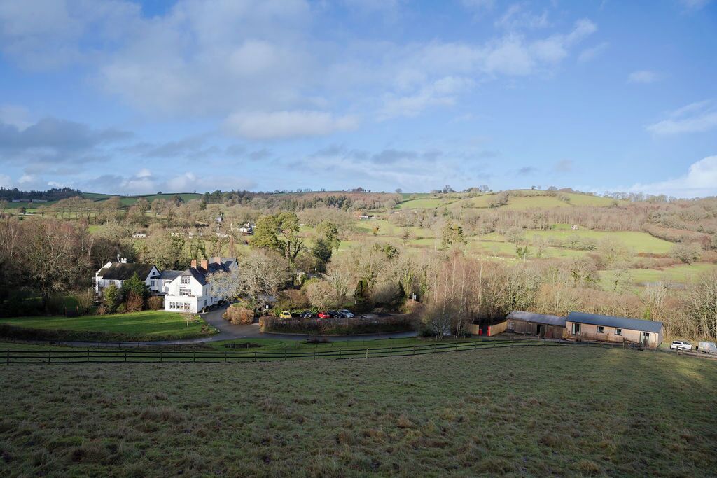 Ländliche Landschaft mit einem weißen Haus, einem Stall und einem eingezäunten Feld.