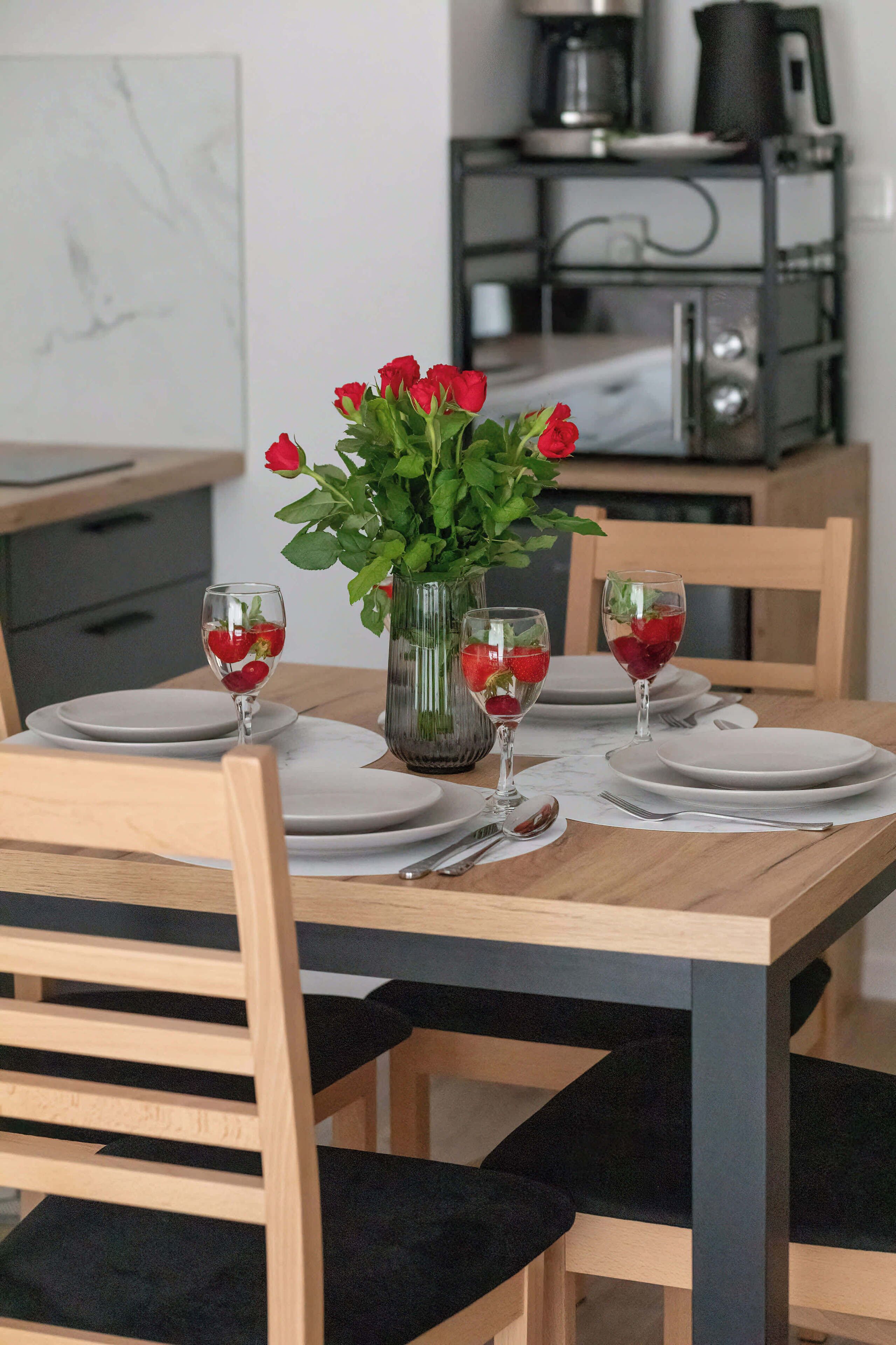 A dining table set with plates, glasses, and a vase with flowers.