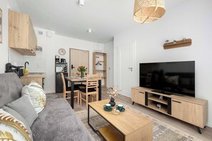 Moderni olohuone, jossa on sohva, sohvapöytä, televisio ja keittiöalue.