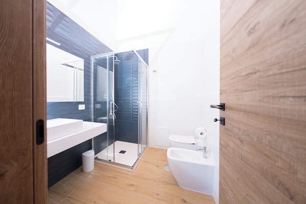 Ein modernes Badezimmer mit einer Duschkabine aus Glas, einem weißen Waschbecken und einem Bidet.