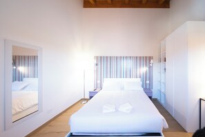 Ein modernes Hotelzimmer mit einem großen Bett, einem Nachttisch, einem Kleiderschrank und einer gestreiften Wanddekoration.