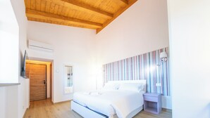 A bedroom with a wooden ceiling, a bed, a bedside table, a wall-mounted TV, and a striped curtain.