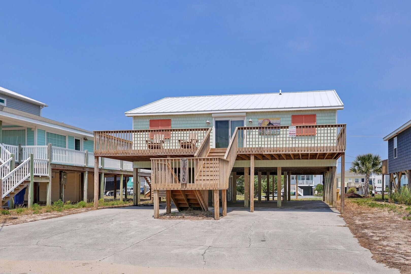 Une propriété située en bord de mer, avec un bâtiment à deux étages, des allées en bois et un ciel dégagé.
