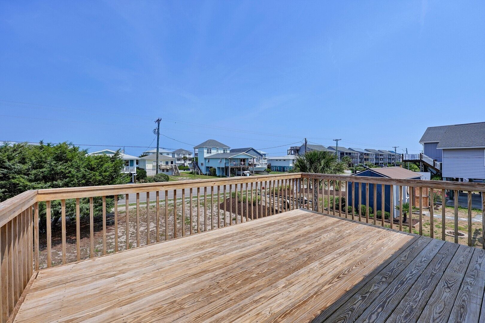 Um deck de madeira com vista para edifícios residenciais e um céu claro.