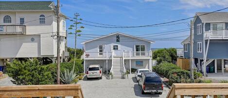A two-story building with a balcony, a garage, and a driveway with parked cars.
