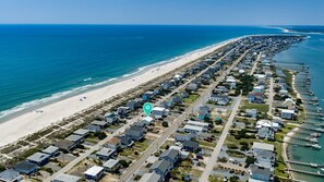 An aerial view of a coastal residential area with houses, a beach, and a marina.