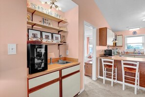 A compact kitchen with a refrigerator, a sink, and a small dining area with two chairs.