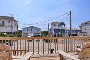 A wooden deck with chairs, a view of houses, and a clear sky.
