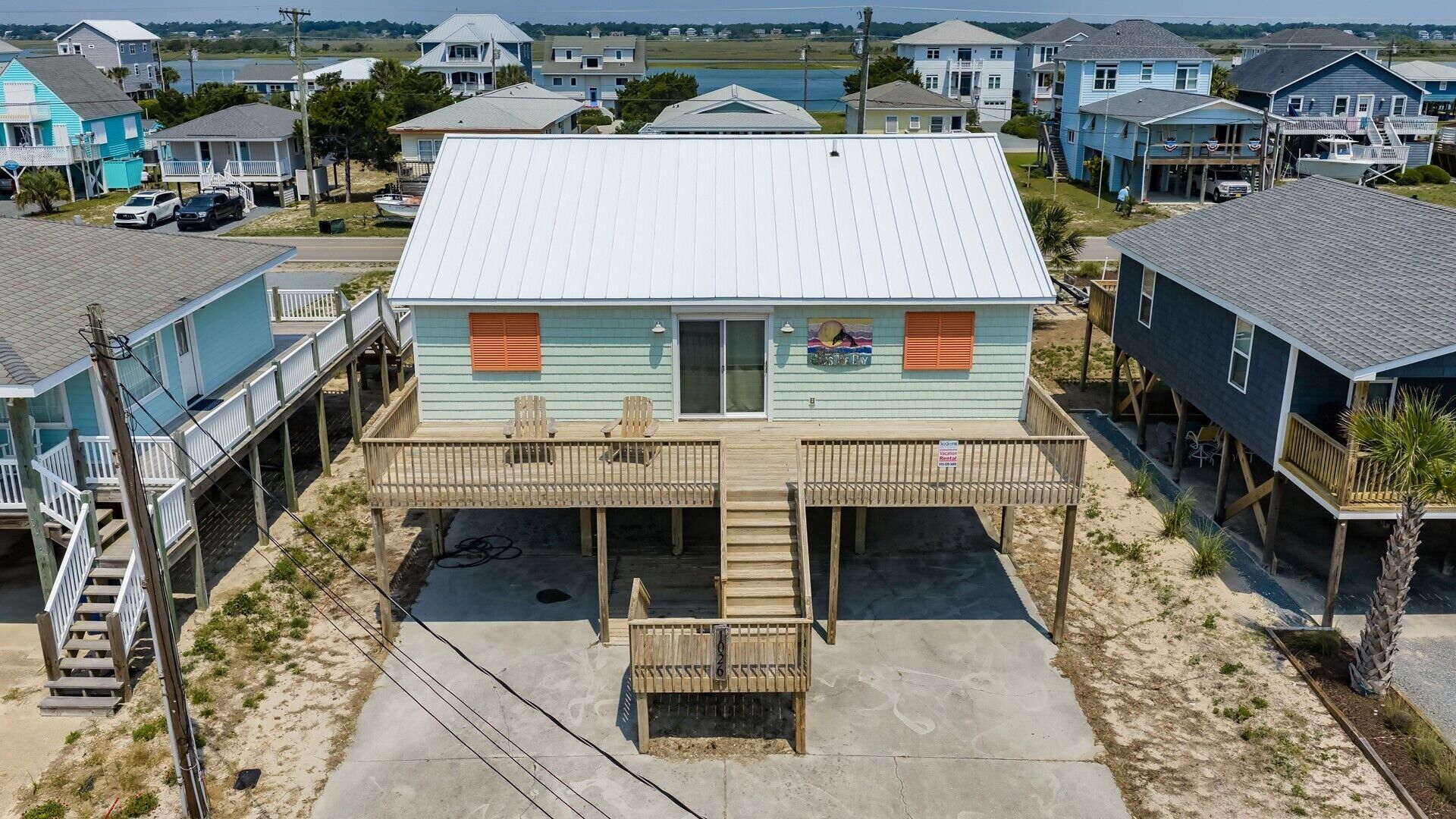 Une maison située en bord de mer, dotée d’une terrasse couverte, d’un petit porche et offrant une vue sur l’océan.