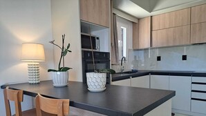 Ett modernt kök med en köksö i mitten, trästolar och en lampa.