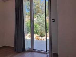 A room with a sliding glass door leading to an outdoor area with rocks and greenery. - VROMOLITHOS VIEW HOUSE: Your Stylish Getaway in Leros (Leros)