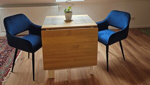 A room with a skylight, a wooden table, two blue chairs, and a potted plant. - Quiet attic studio in Cologne-Holweide, a 2-minute walk to the S-Bahn station for Deutz/Messe (Köln)