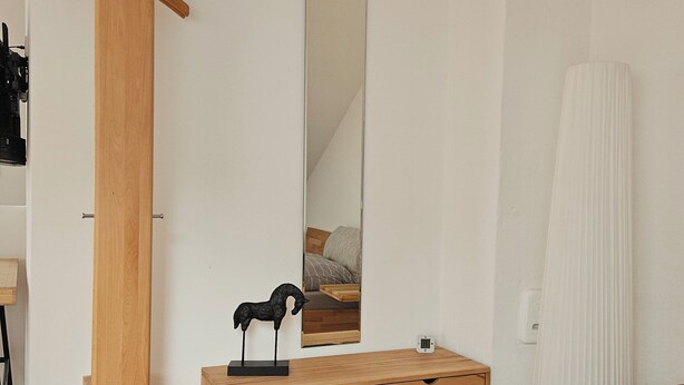 A bedroom with a wooden dresser, a mirror, a bedside table, a rug, and a wooden chair. - Quiet attic studio in Cologne-Holweide, a 2-minute walk to the S-Bahn station for Deutz/Messe (Köln)