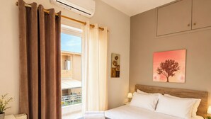 A hotel room with a bed, a desk, a chair, a window with curtains, an air conditioning unit, and a painting on the wall. - Villa Morea With Pool Near Chania City (Chania)