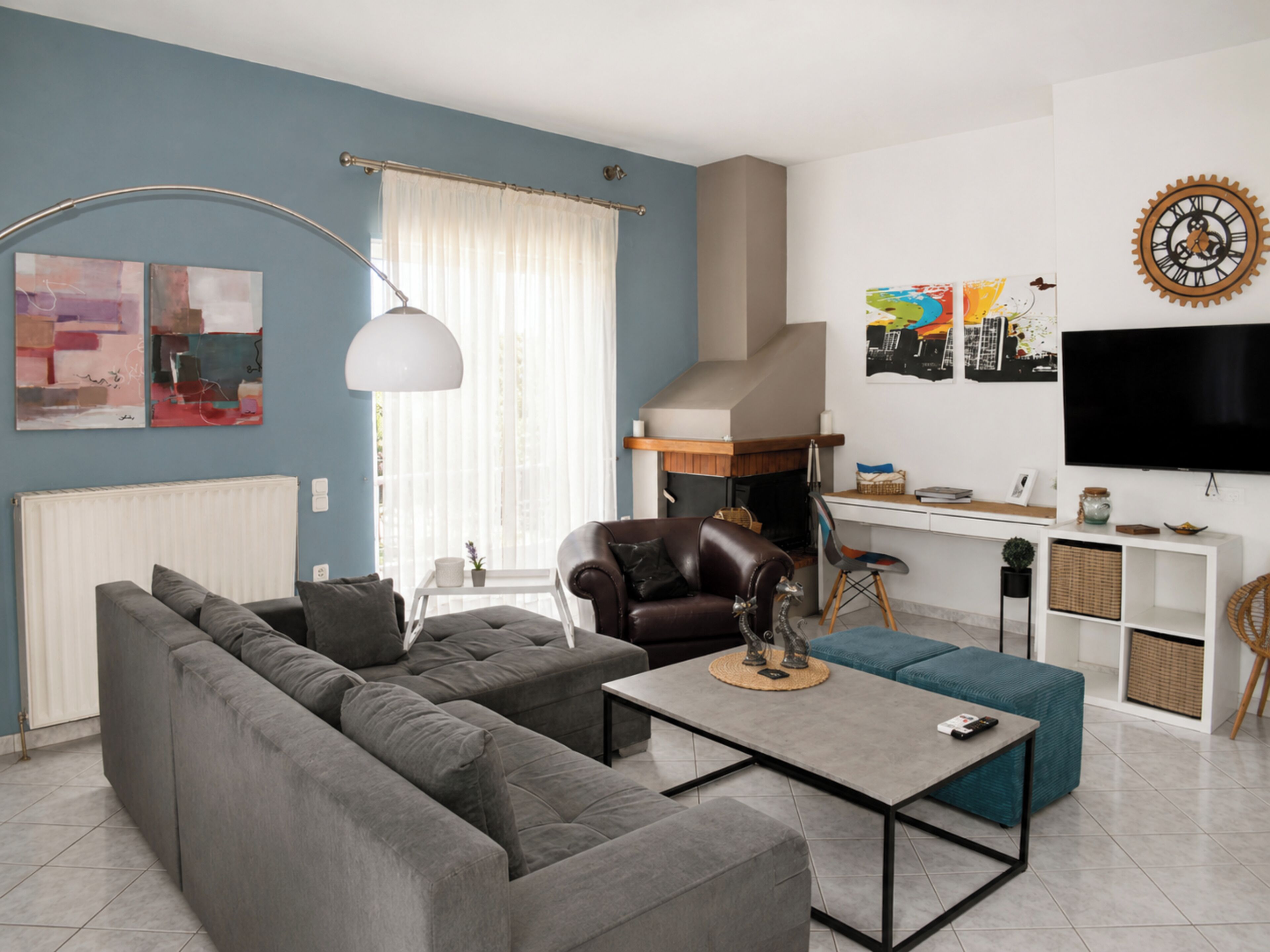 Una sala de estar moderna con sofá, mesa de centro, chimenea, televisor y obras de arte en las paredes.
