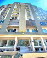 Ein mehrstöckiges Gebäude mit der Aufschrift 'Irenic II' auf der Fassade, mit Balkonen, Fenstern und einer Treppe zum Eingang.