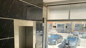 A modern interior with a marble wall, a glass door leading outside, and a tiled floor.