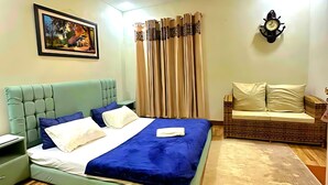 A bedroom with a bed, a nightstand, a wall-mounted clock, and a ceiling fan.