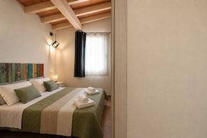 A bedroom with a bed, pillows, a bedside table, a wall-mounted light, and a window with curtains. - Mar | House in Solanas between sea and nature (Cuili Murvoni)