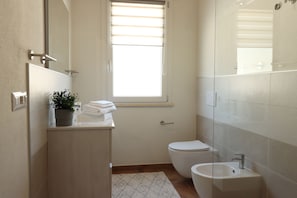 A small, modern bathroom with a toilet, sink, and a window. - Mar | House in Solanas between sea and nature (Cuili Murvoni)