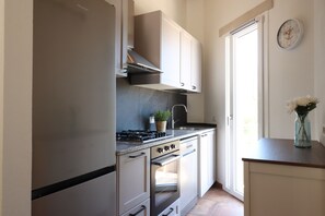 A kitchen with a stove, oven, and cabinets. - Mar | House in Solanas between sea and nature (Cuili Murvoni)