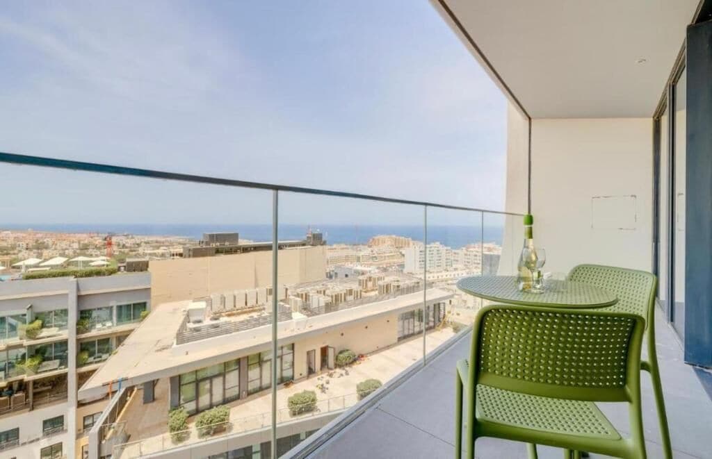 A balcony with a view of the city and the sea.