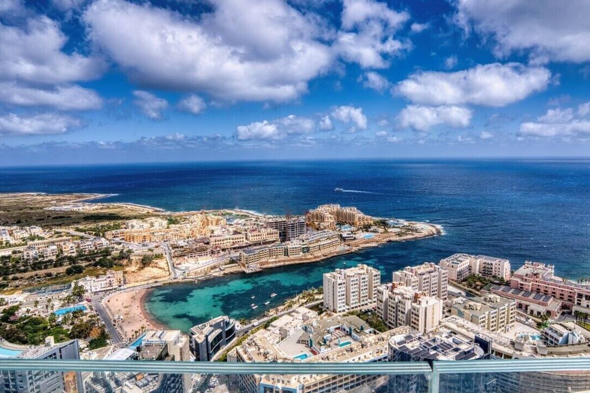 Un paysage urbain côtier avec un port de plaisance, des bâtiments et une vue sur la mer.