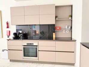A modern kitchen with a built-in oven, a coffee machine, and a fire extinguisher. - Mercury tower suites by Asignatures (St. Julian's)