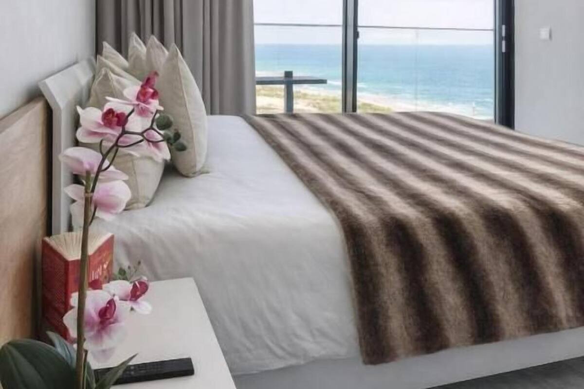 Une chambre moderne avec un grand lit, une vue sur la mer et un balcon.