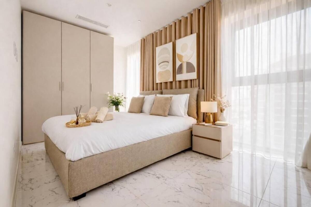 Une chambre à coucher comprenant un lit, des tables de chevet, une armoire et des œuvres d’art accrochées au mur.