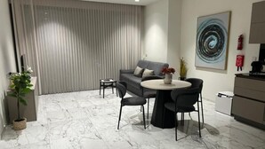 A modern living room with a grey sofa, round coffee table, and black chairs. - Mercury tower suites by Asignatures (St. Julian's)