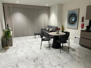 A modern living room with a grey sofa, round coffee table, and black chairs.