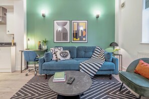 A living room with a sofa, coffee table, and a kitchen area in the background. - Kula London Tower Bridge (London)