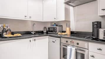 A modern kitchen with white cabinets, a Bosch dishwasher, a microwave, a coffee maker, and a toaster.