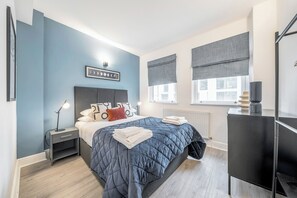 A modern bedroom with a bed, bedside tables, a desk, and a radiator. - Kula London Tower Bridge (London)