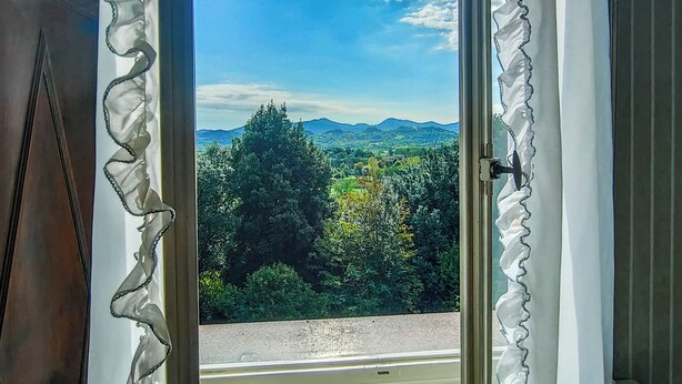 Una ventana con vistas a un paisaje boscoso y montañas distantes.