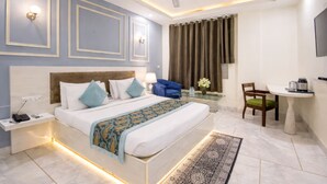 A hotel room with a bed, bedside table, lamp, chair, and a small table with a coffee maker. - OPO Essential Alpino (New Delhi)