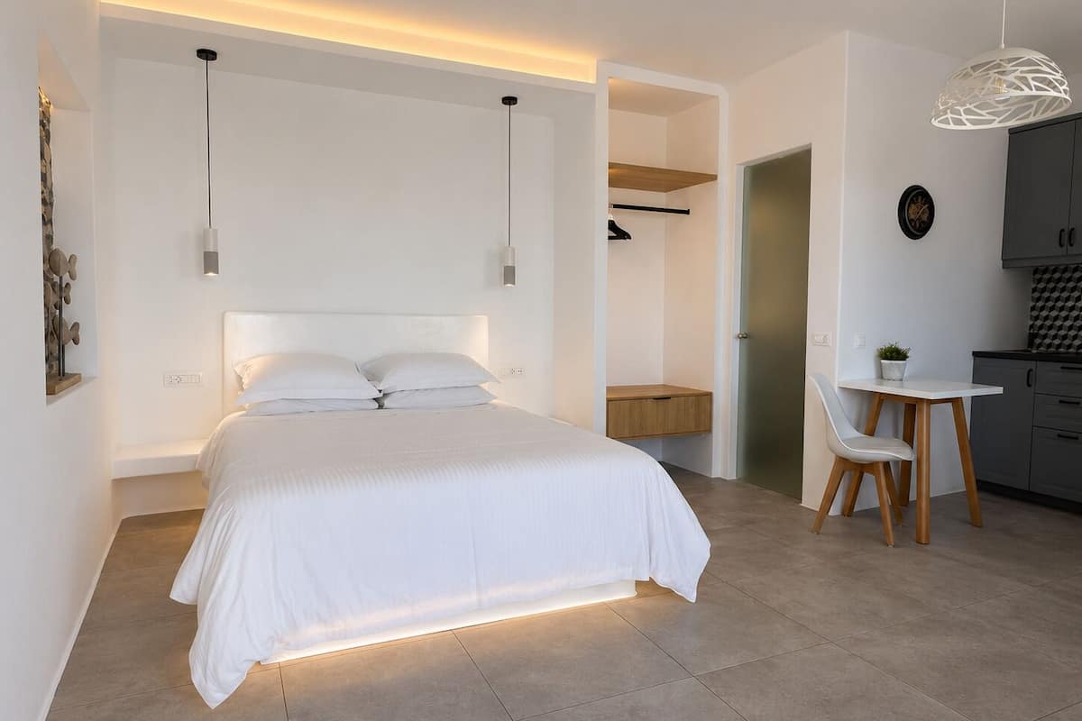 A modern bedroom with a large bed, bedside tables, a desk, and a chair.