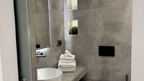 A modern bathroom with a large mirror, two sinks, a toilet, and a small plant. - Aegean View Apartments (Ornos)
