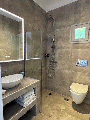 A modern bathroom with a glass-enclosed shower, a large sink, and a toilet. - Aegean View Apartments (Ornos)
