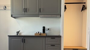 A modern kitchen with grey cabinets, a coffee machine, and a small wooden box on the counter. - Aegean View Apartments (Ornos)