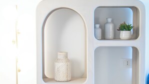 A white, wall-mounted shelf unit with multiple compartments, including a vase and small potted plants. - New Farmhouse TENUTA MARELLA immersed in the Green at the gates of Rome (Lazio)