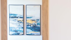 A room with a blue sofa, a yellow pillow, and two framed abstract paintings on the wall. - New Farmhouse TENUTA MARELLA immersed in the Green at the gates of Rome (Lazio)
