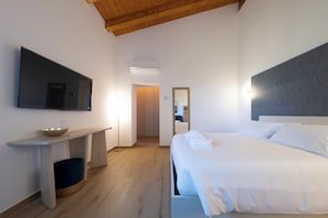 Ein Hotelzimmer mit Bett, Flachbildfernseher, Nachttisch, Spiegel und Holzboden.