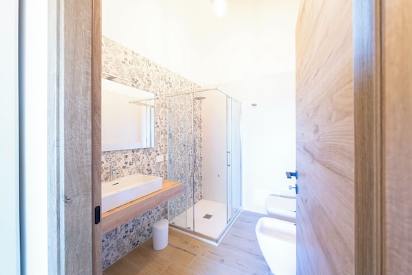 Ein modernes Badezimmer mit Dusche, Waschbecken und Spiegel.