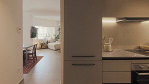 A modern kitchen with a marble countertop, built-in oven, and a dining area with a table and chairs. - AIORA Urban Oasis - Rooftop Jacuzzi & BBQ (Thessaloniki)