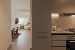 A modern kitchen with a marble countertop, built-in oven, and a dining area with a table and chairs. - AIORA Urban Oasis - Rooftop Jacuzzi & BBQ (Thessaloniki)