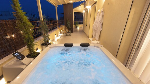 A hot tub with a digital control panel, surrounded by potted plants and seating. - AIORA Urban Oasis - Rooftop Jacuzzi & BBQ (Thessaloniki)